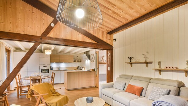 A cozy living room with a sofa, a coffee table, and a dining area with chairs and a table. - Charming Apartment for 6 in the Heart of Les Gets Village, Close to Slopes (Les Gets)