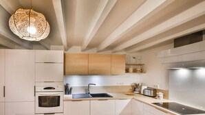 A modern kitchen with white cabinets, a built-in oven, a sink, and a coffee maker. - Charming Apartment for 6 in the Heart of Les Gets Village, Close to Slopes (Les Gets)