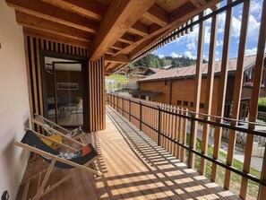 Un balcon en bois offrant une vue sur des bâtiments traditionnels et un ciel dégagé.