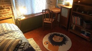 Une chambre confortable avec un lit, un bureau, une chaise, une bibliothèque et un tapis à motifs de lion.