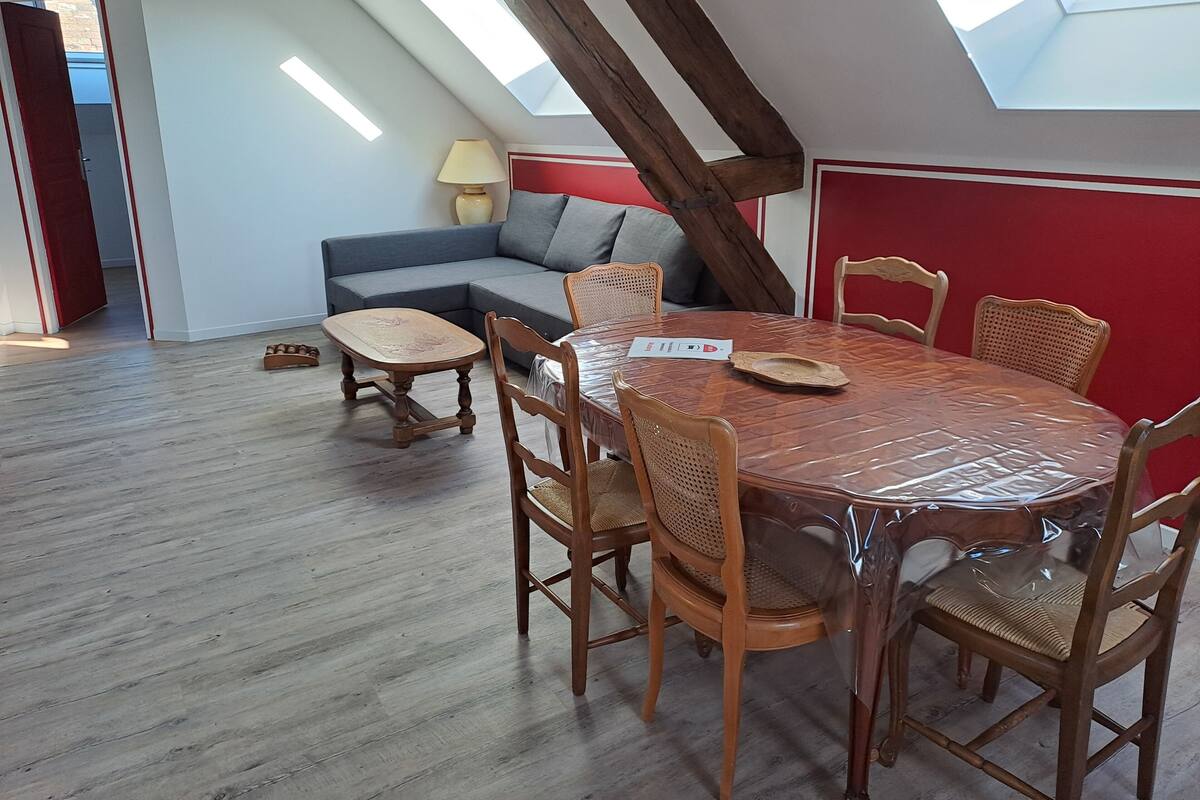 A dining area with a round table, wooden chairs, and a high ceiling with skylights.