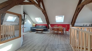 A loft-style room with a dining area, a sofa, and a TV. - Le km99 (Pont-sur-Yonne)