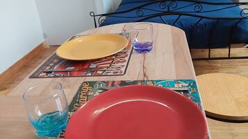Een eettafel met een rood bord, een geel bord en een glas met blauwe vloeistof. De tafel heeft een placemat met een vintage automotief thema.