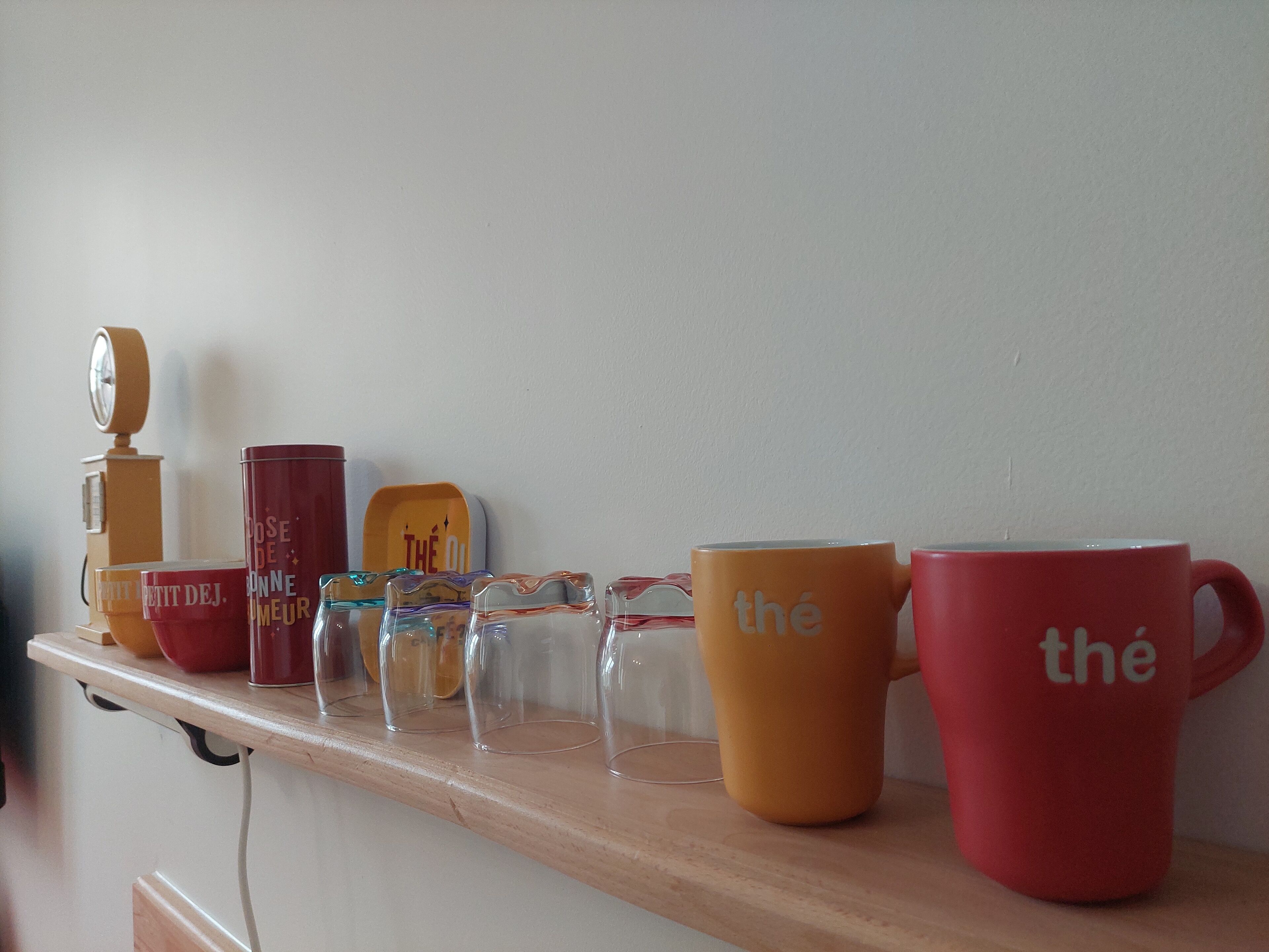 Una estantería con diferentes tazas y una máquina de café.
