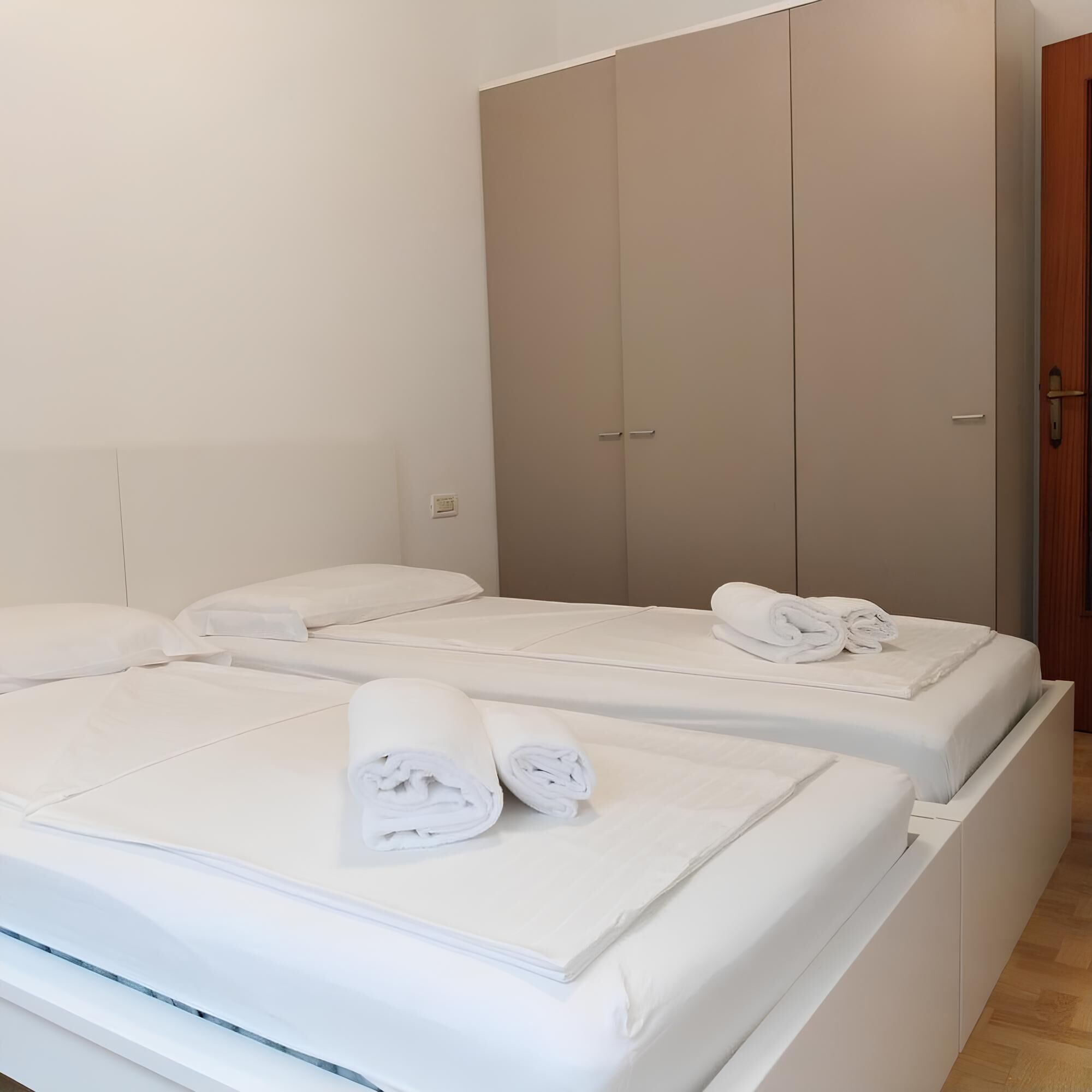 A hotel room with two beds, each with neatly folded white towels.