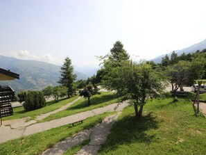 A park with a paved path, benches, and trees.