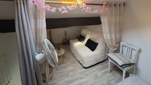 A bedroom with a skylight, a bed, a chair, a fan, and a small table with a plant. - Cozy pavilion in Argelès-sur-Mer, near the sea (Argelès-sur-Mer)