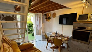 A cozy living room with a sofa, a dining table set for four, and a kitchen area with a microwave and oven. - Cozy pavilion in Argelès-sur-Mer, near the sea (Argelès-sur-Mer)