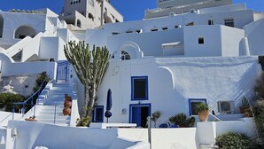 Un bâtiment blanc agrémenté de touches de bleu, avec un escalier et des plantes en pot.