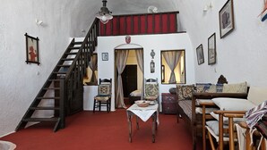 Une pièce avec un escalier en bois, une table à manger avec des chaises, un canapé et un lit.