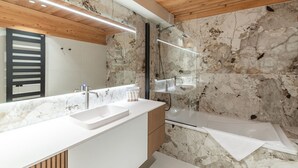 A modern bathroom with a wooden ceiling, marble walls, a double sink vanity, and a glass shower enclosure. - Luxury chalet Alpe d'Huez with spa and ski-in/ski-out (Huez)