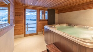 A wooden cabin with a hot tub, wooden walls, and a view of snow-covered mountains. - Luxury chalet Alpe d'Huez with spa and ski-in/ski-out (Huez)
