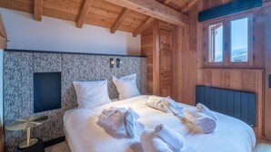 A wooden cabin bedroom with a bed, pillows, and towels. - Luxury chalet Alpe d'Huez with spa and ski-in/ski-out (Huez)