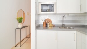 Une cuisine moderne avec des armoires blanches, un évier en acier inoxydable et un four à micro-ondes.