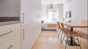 Une cuisine moderne avec des meubles blancs et un coin repas comprenant une table en bois et des chaises en osier.