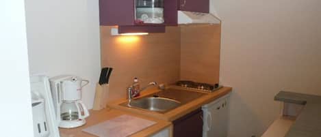 A compact kitchen with a sink, a coffee maker, and a microwave.
