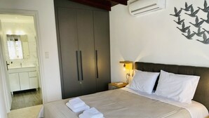 A hotel room with a bed, a nightstand, an air conditioner, and a wall with a leaf pattern.