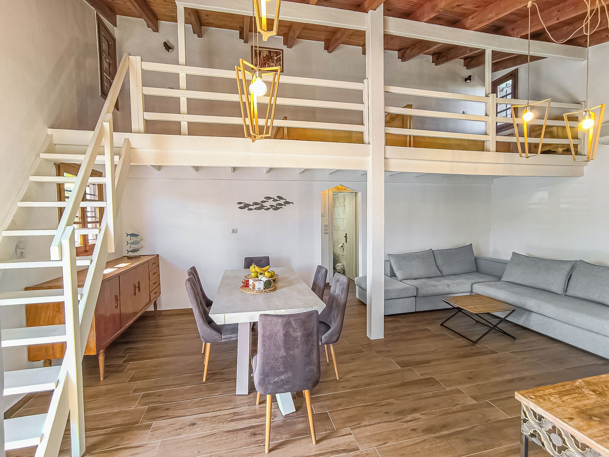 A spacious loft with a dining area, a sofa, and a staircase.