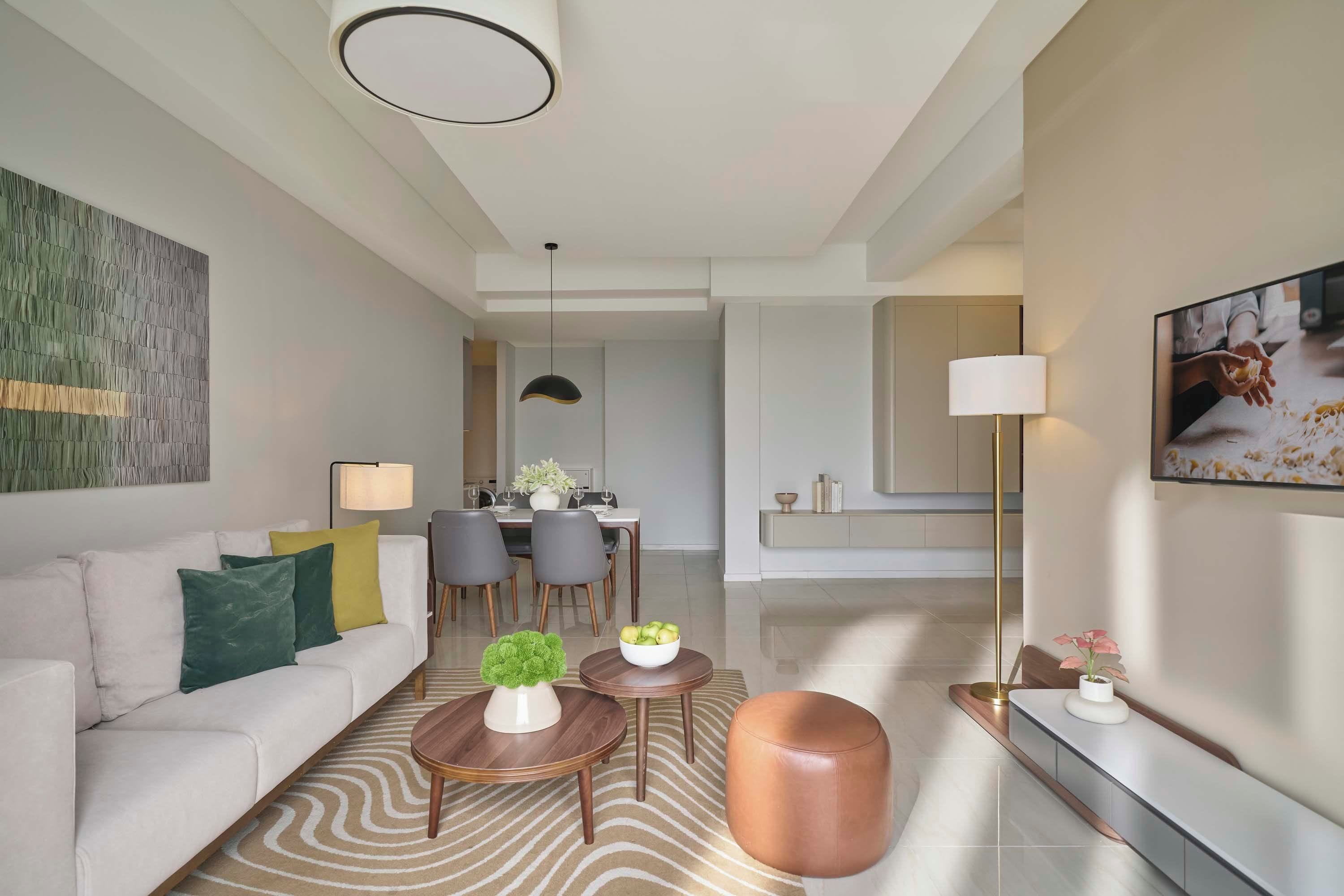 A modern living room with a sofa, coffee table, ottoman, and a dining area with chairs and a table.