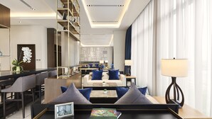 Un hall d’hôtel moderne avec un ensemble de canapés, une table basse et une bibliothèque.