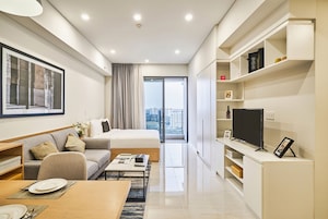 Una habitación de hotel moderna con cama, sofá, mesa de comedor y televisor.