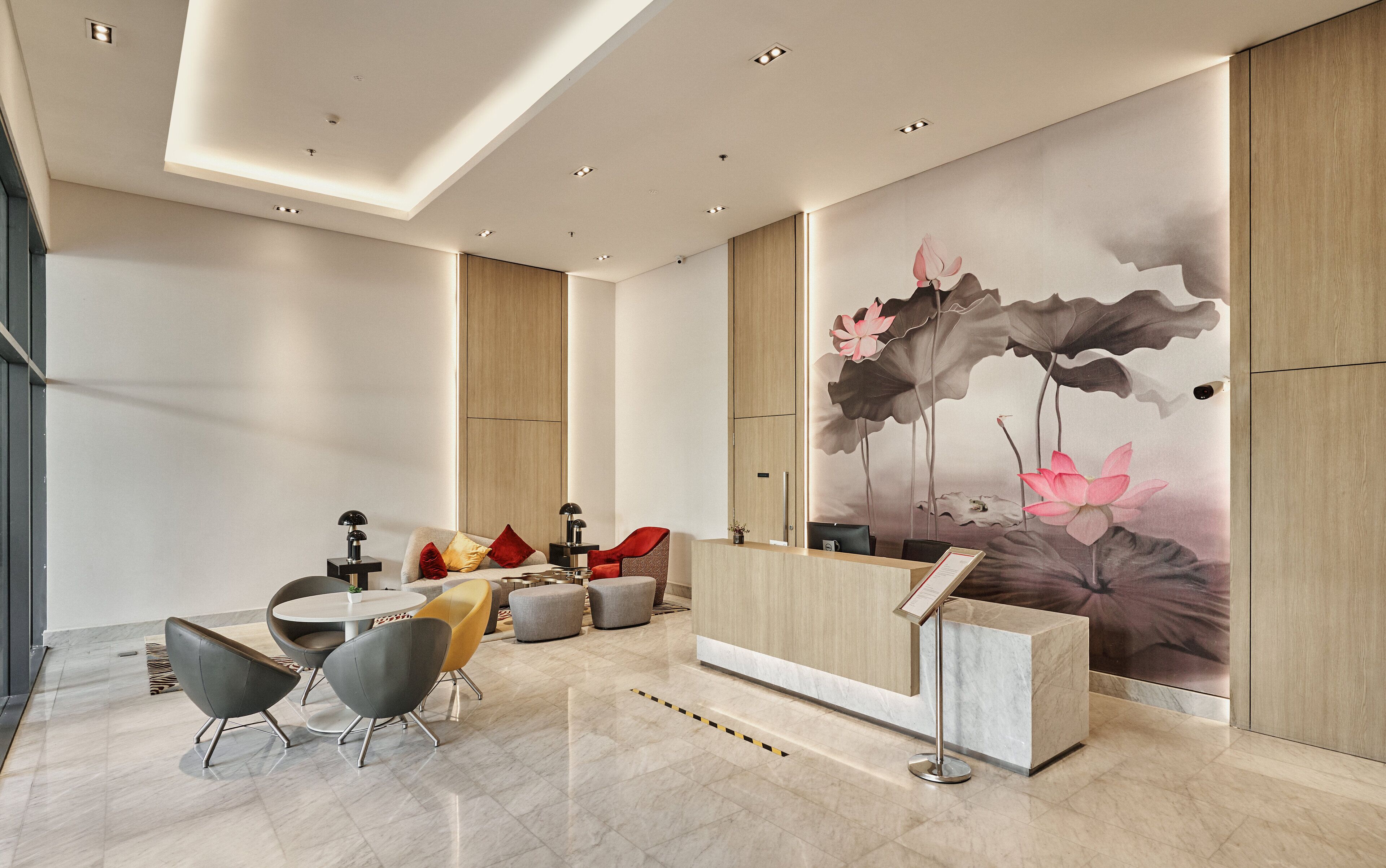 A modern reception area with a marble floor, a reception desk, and a wall mural of lotus flowers.