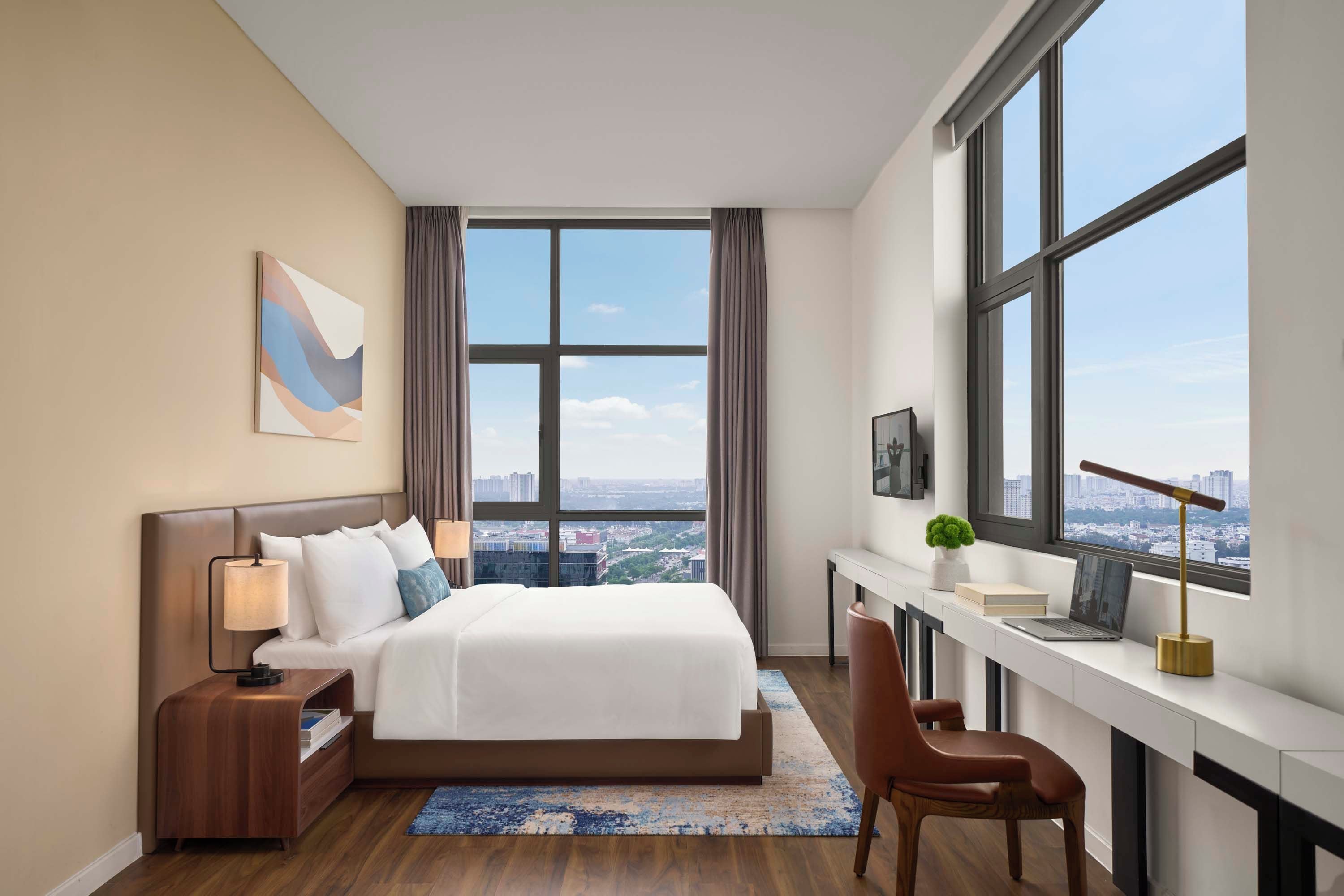 Una habitación de hotel moderna con una cama grande, un escritorio y vistas a la ciudad.