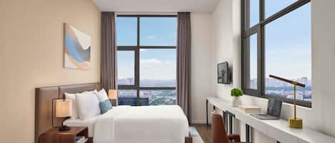 Una habitación de hotel moderna con una cama grande, un escritorio y vistas a la ciudad.