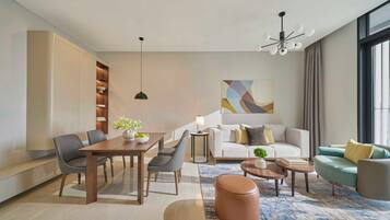 A modern living room with a dining area, a sofa set, a coffee table, and a large window providing natural light.