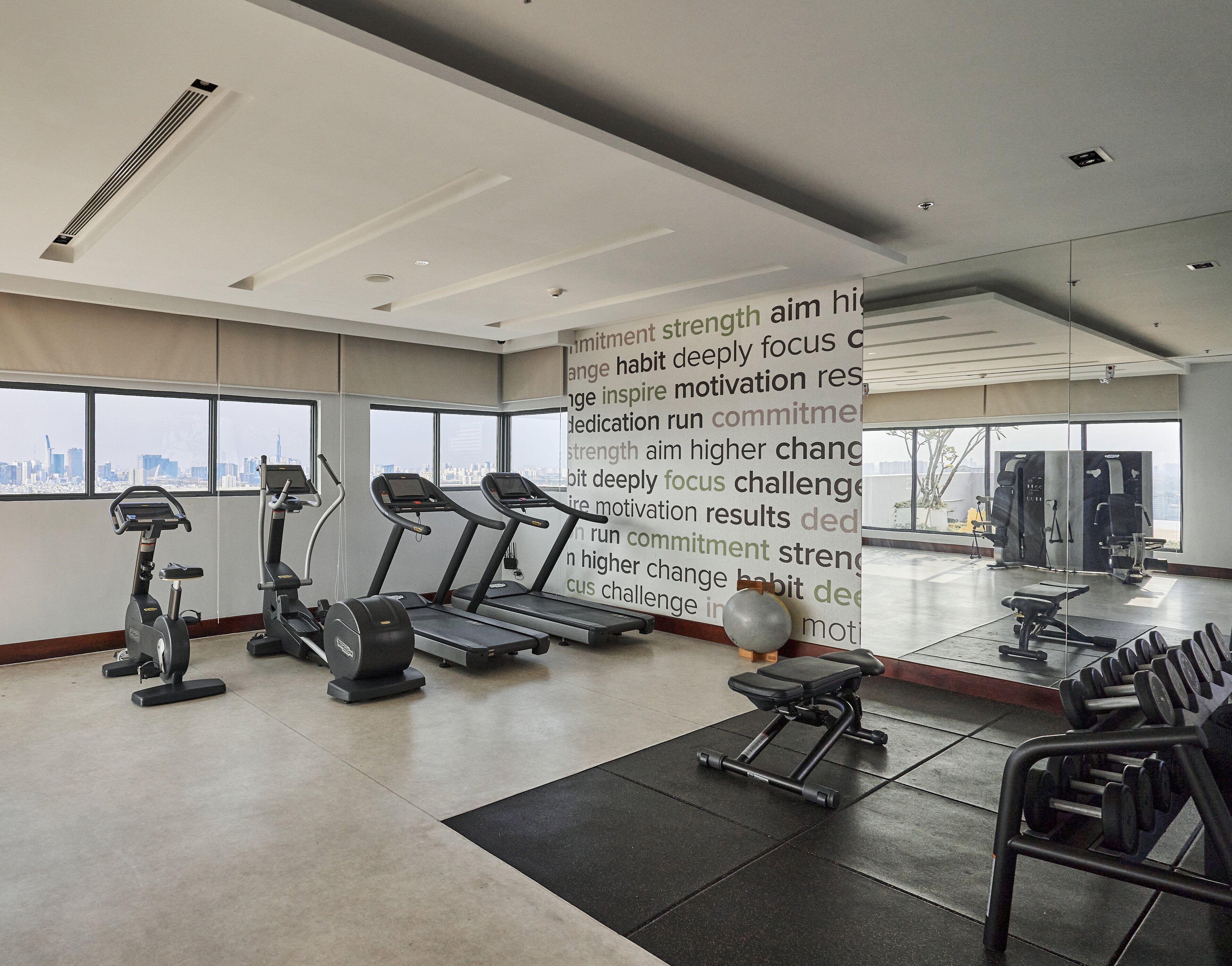 A modern gym with treadmills, elliptical machines, and free weights.