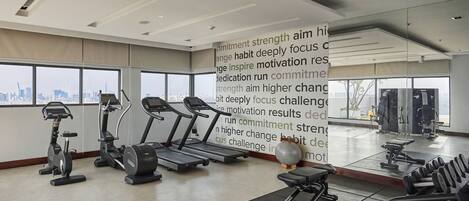 A modern gym with treadmills, elliptical machines, and free weights.