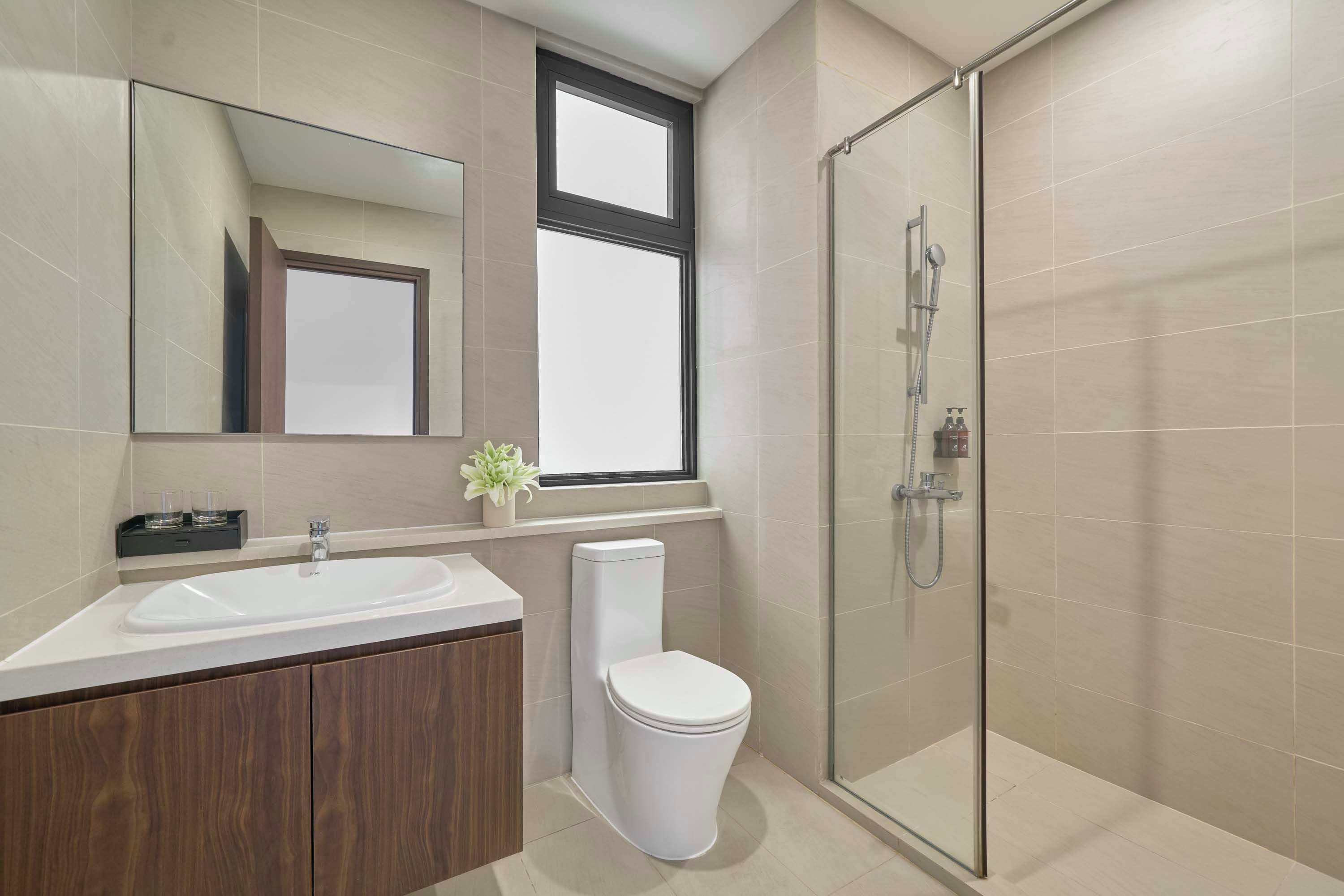 Un baño moderno con ducha envuelta en vidrio, un lavabo blanco y un inodoro.
