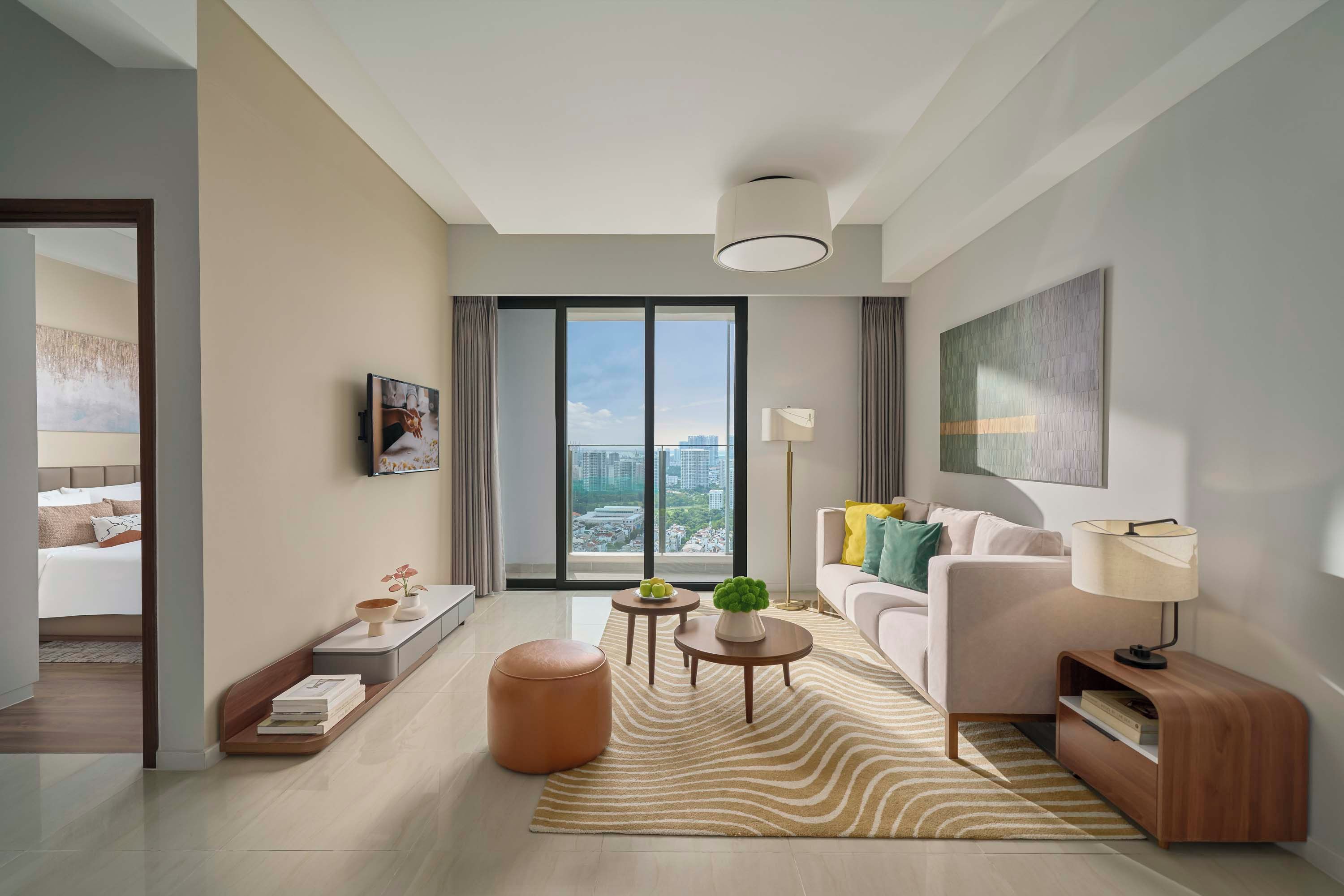 Ein modernes Wohnzimmer mit einer Couch, einem Couchtisch und Blick auf die Stadt durch große Fenster.