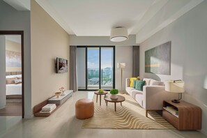 A modern living room with a sofa, a coffee table, and a view of the city through large windows. - RichLane Residences Managed by The Ascott Limited (Ho Chi Minh City)