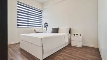 A bedroom with a bed, bedside table, and a window with blinds.