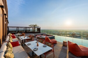 Terraza en la azotea con mobiliario exterior, una chimenea y vistas panorámicas de la ciudad.