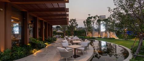 An outdoor patio area with seating, a small pond, and a wooden pergola.