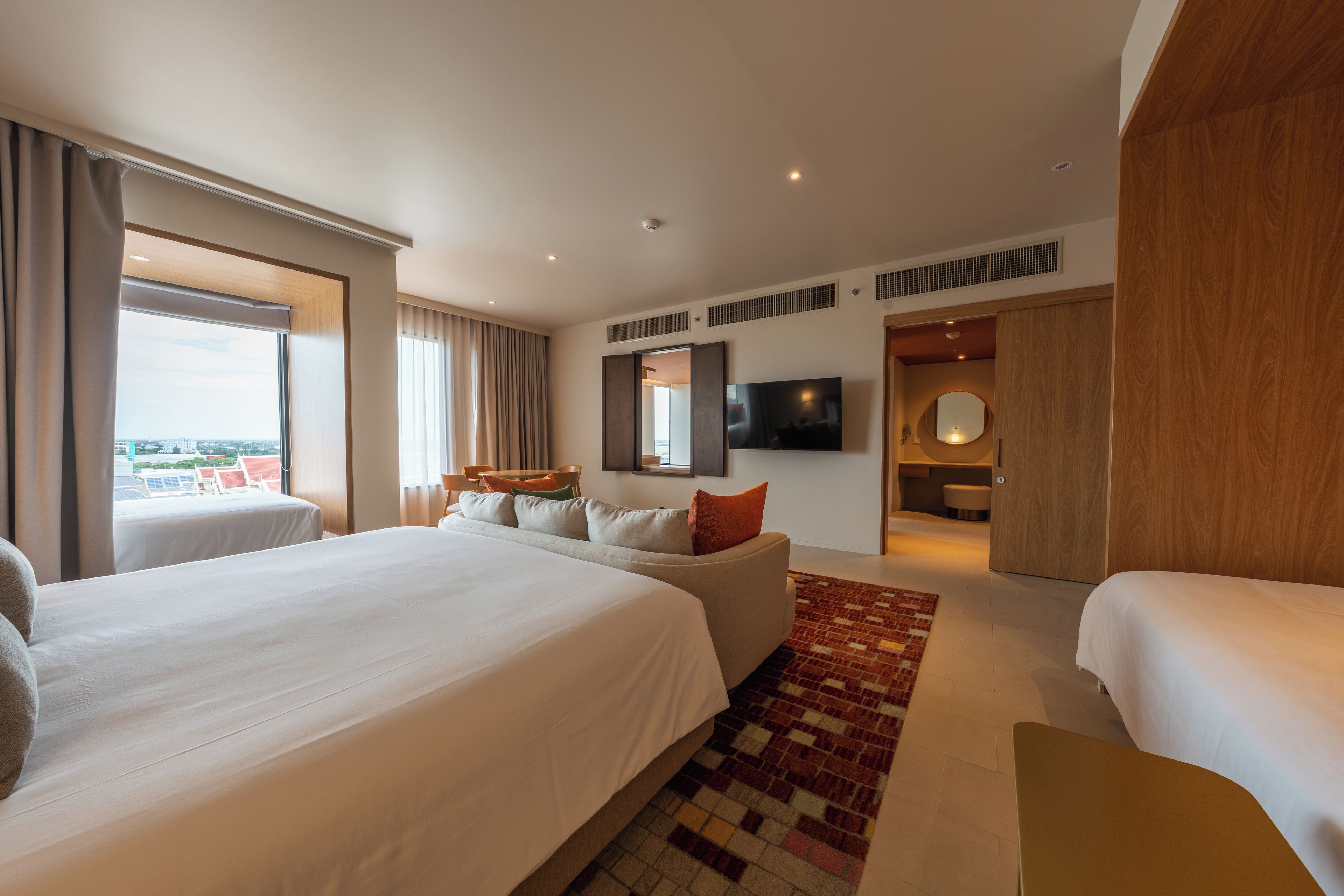 Een hotelkamer met twee bedden, een televisie, een zithoek en uitzicht op de stad.