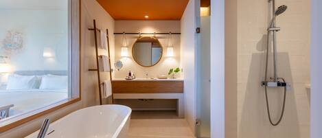 A modern bathroom with a freestanding bathtub, a vanity with a mirror, and a shower area.