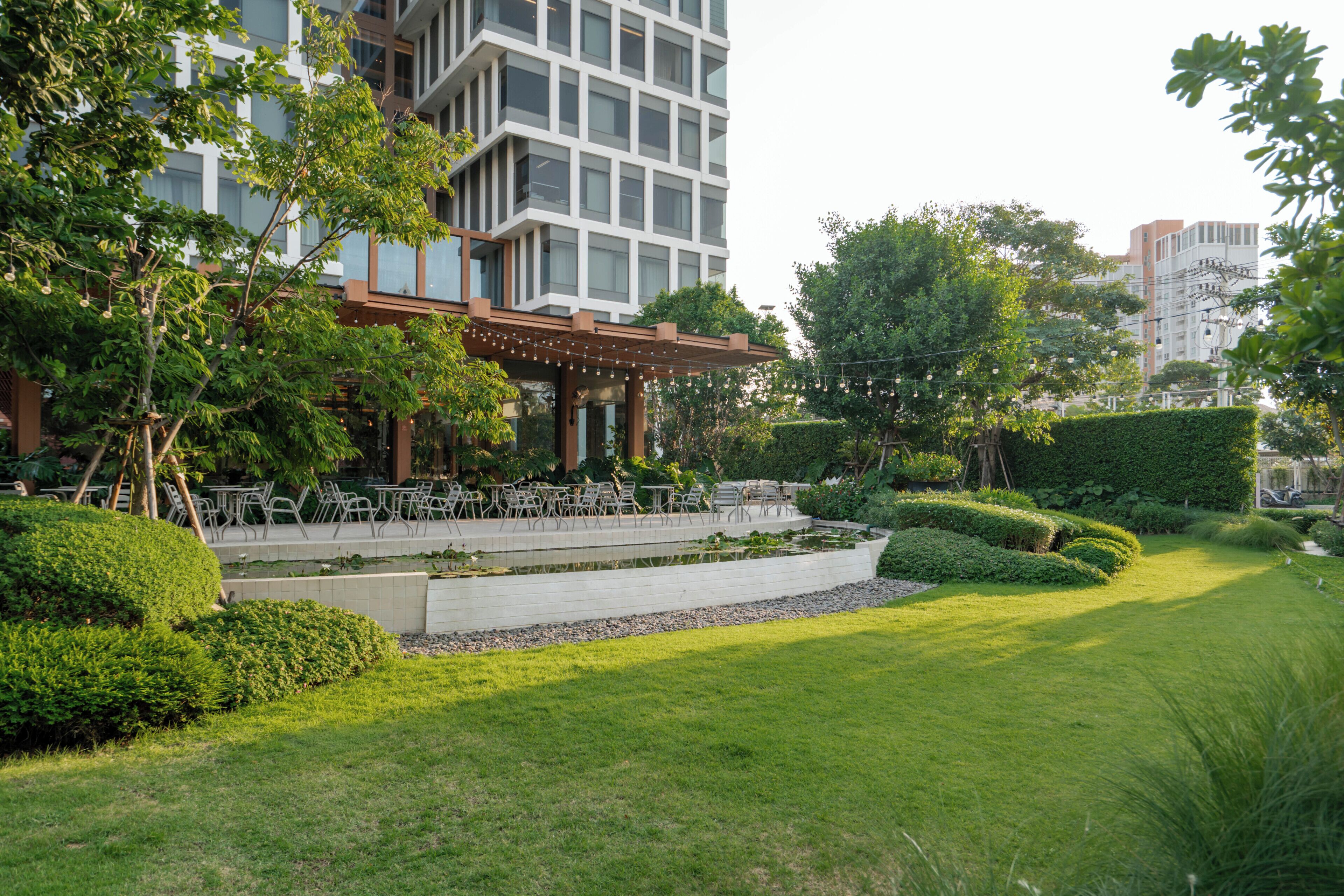 Un edificio moderno con un patio que cuenta con mobiliario exterior y una fuente de agua.