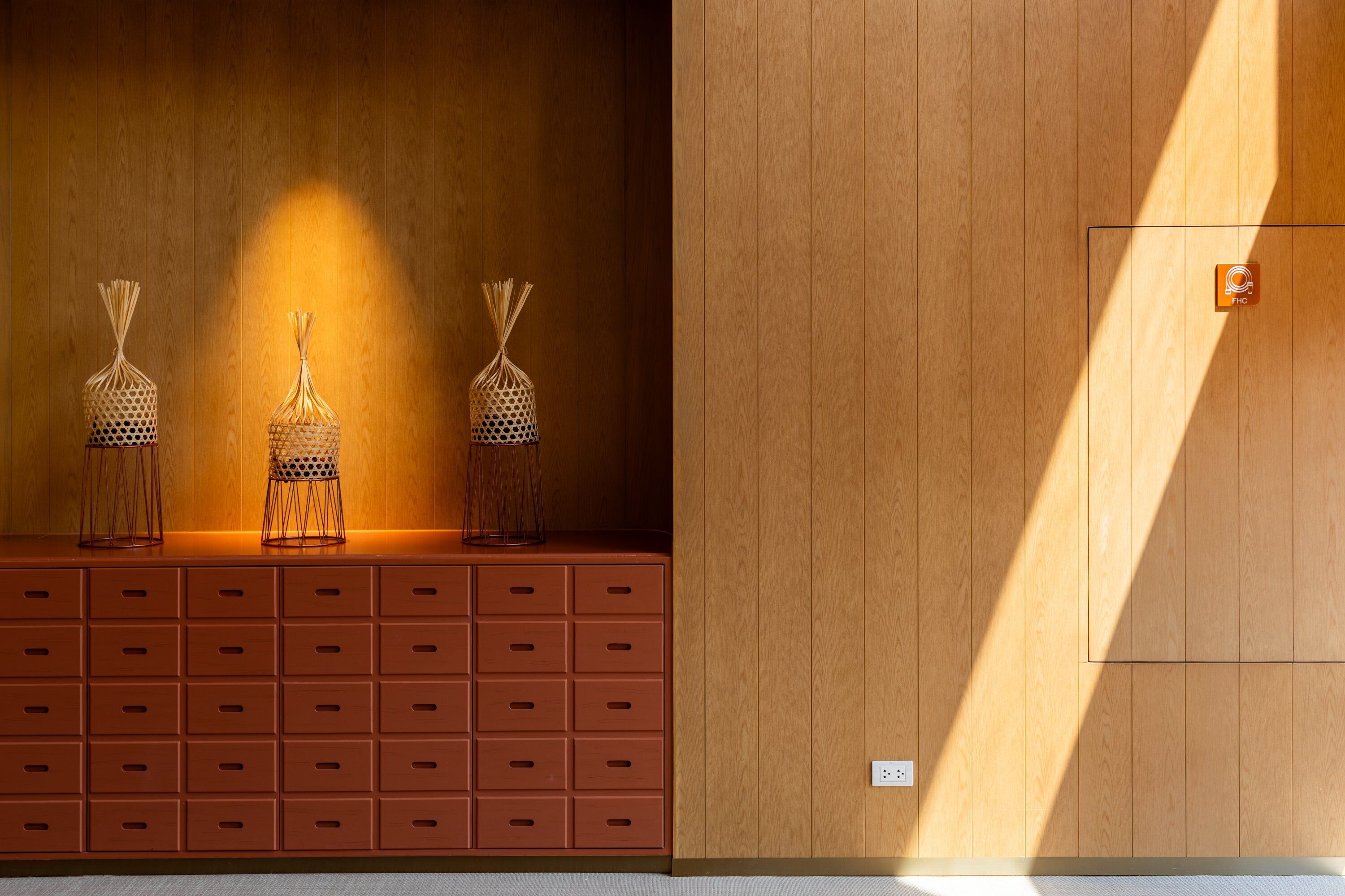 A wooden wall with a built-in shelf holding three decorative baskets.