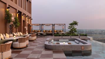 Una terraza en la azotea con mobiliario exterior, piscina y vistas a la ciudad.