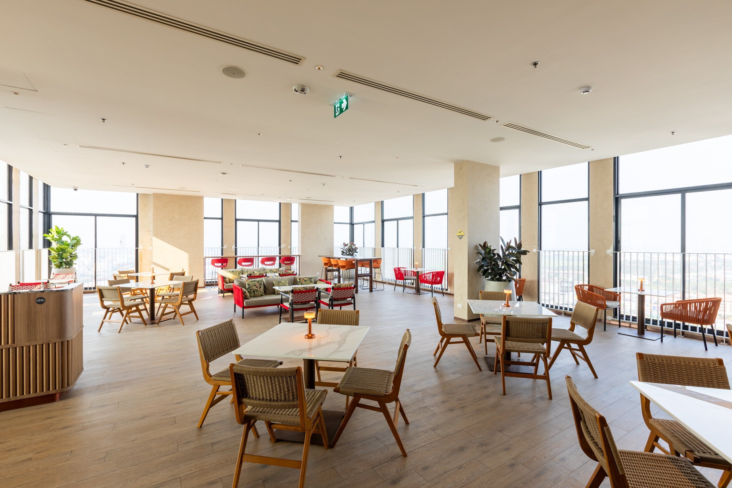 A spacious indoor area with multiple seating arrangements, including tables and chairs, and large windows providing natural light.