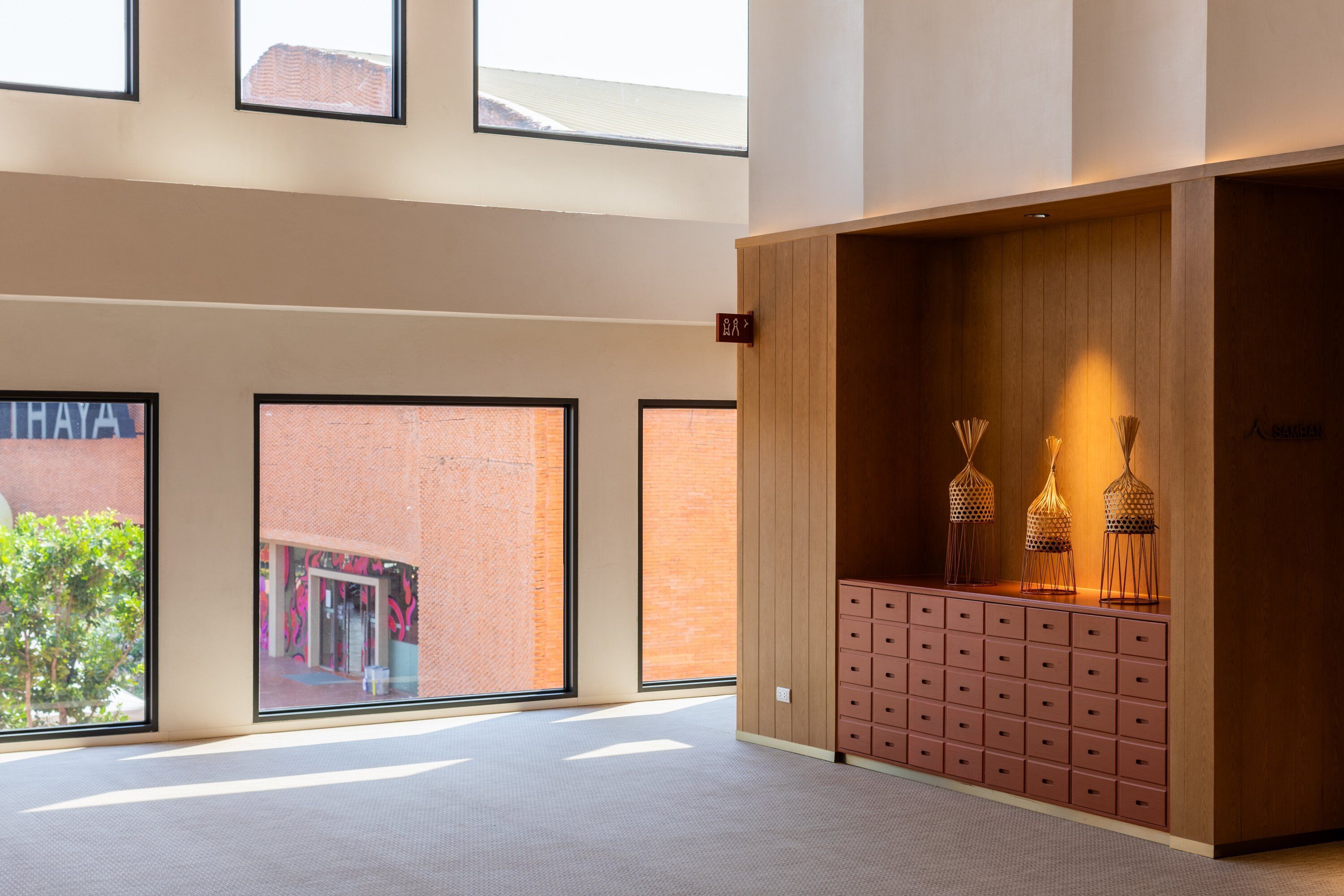 A spacious lobby with large windows, a wooden reception desk, and a patterned floor.