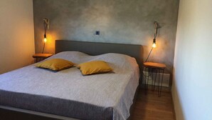 A bedroom with a bed, two bedside tables, and two wall-mounted lamps.
