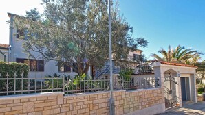 Un edificio residencial con un muro de ladrillo, una reja de metal y un árbol en la parte delantera.