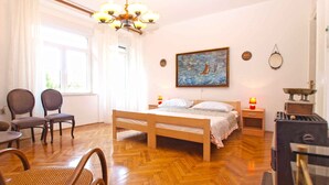 A bedroom with a wooden bed, a painting on the wall, a chandelier, and a stove. - Holiday apartment with air conditioning (Pula)