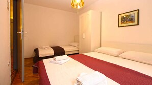 Une chambre d’hôtel avec un lit, une armoire, un tableau au mur et une porte donnant sur une autre pièce.