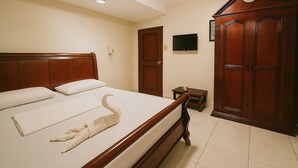 A hotel room with a wooden bed, a television on the wall, and a wardrobe. - Goland Pension House and Dormitory by SMS Hospitality (Cebu City)
