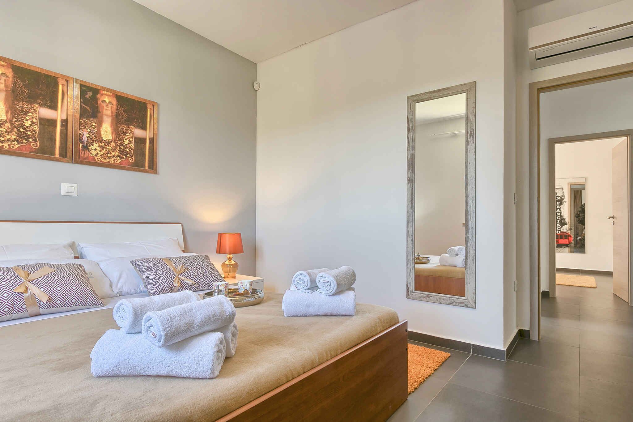 Ein modernes Hotelzimmer mit einem großen Bett, einem Nachttisch mit Lampe und einem Spiegel an der Wand.